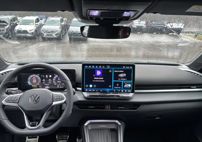 Vue intérieure du tableau de bord du Volkswagen T-Roc gris loup, avec écran tactile central et volant multifonctions.