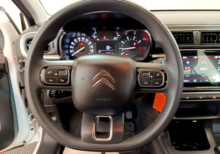 Vue intérieure centrée sur le volant noir d'une Citroën C3 blanche, avec tableau de bord et écran tactile visibles.