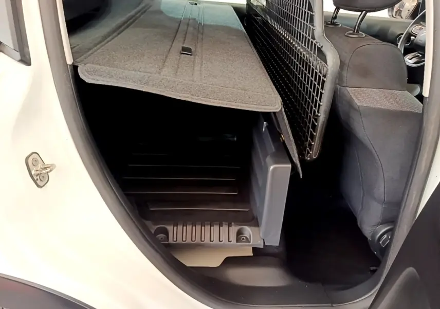 Vue intérieure côté droit du coffre d'une Citroën C3 blanche 2021 avec banquette rabattue et séparation grillagée.