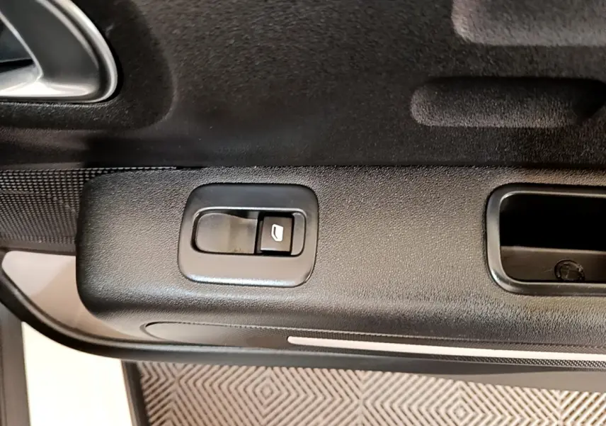 Gros plan sur la commande de lève-vitre côté gauche de la porte intérieure noire d'une Citroën C3 blanche de 2021.