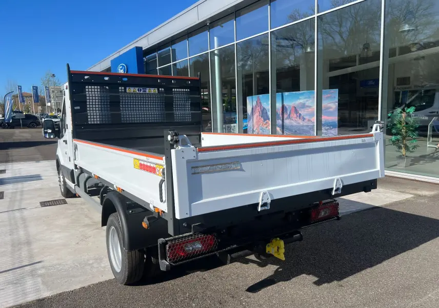 Ford Transit Chassis Cabine blanc vu 3/4 arrière droit, avec benne basculante et coffre, roues jumelées visibles.