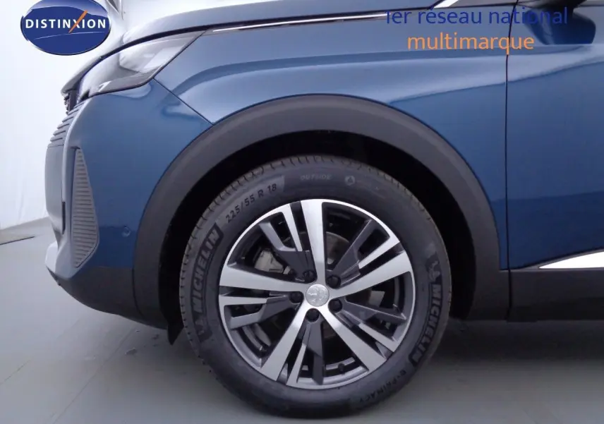 Gros plan sur la roue avant gauche d'un Peugeot 3008 2023 bleu Célèbes Métal avec jante alliage bicolore.