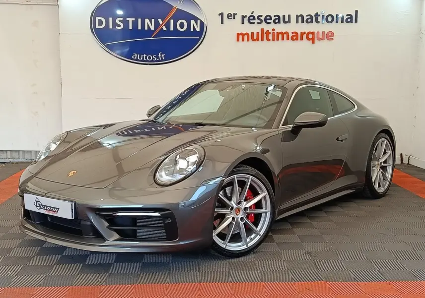Porsche 911 Carrera 4S Coupé gris foncé vue 3/4 avant droit, jantes argent et étriers rouges visibles