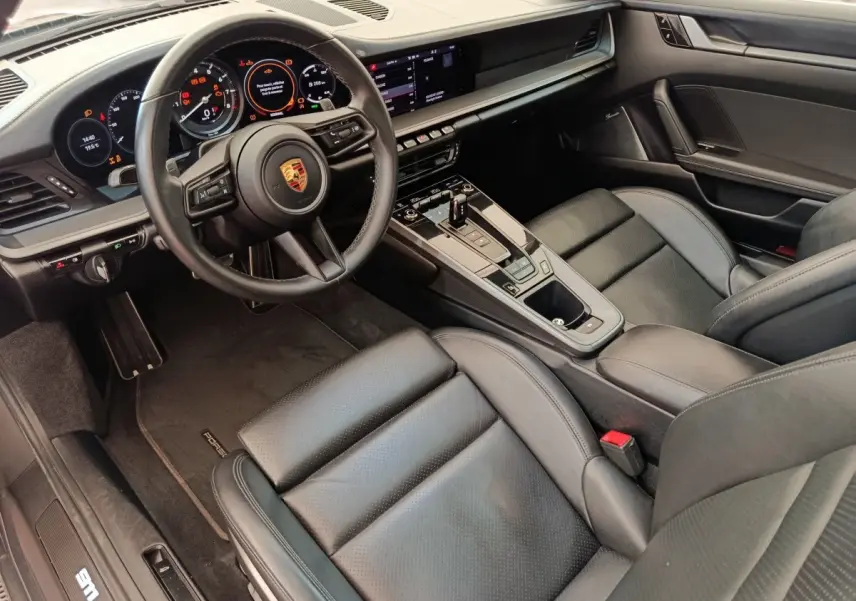 Intérieur noir du Porsche 911 Carrera 4S 2019 vu côté conducteur, avec tableau de bord numérique et volant cuir.