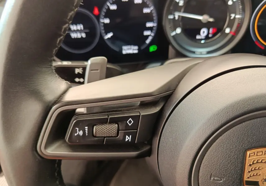 Gros plan sur le volant cuir noir de la Porsche 911 Carrera 4S 2019 avec commandes multifonctions et tableau de bord numérique.