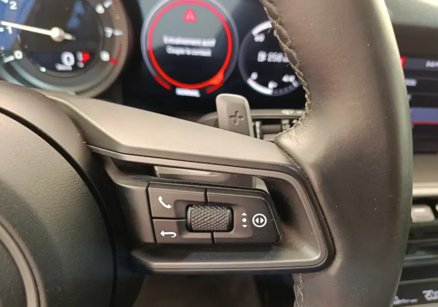 Gros plan sur les commandes au volant cuir noir de la Porsche 911 Carrera 4S Coupé 2019 avec tableau de bord numérique.