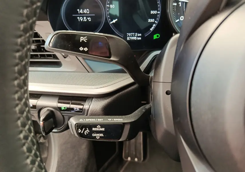 Gros plan sur le volant et les commandes au volant d'une Porsche 911 Carrera 4S Coupé gris foncé, tableau de bord numérique visible.