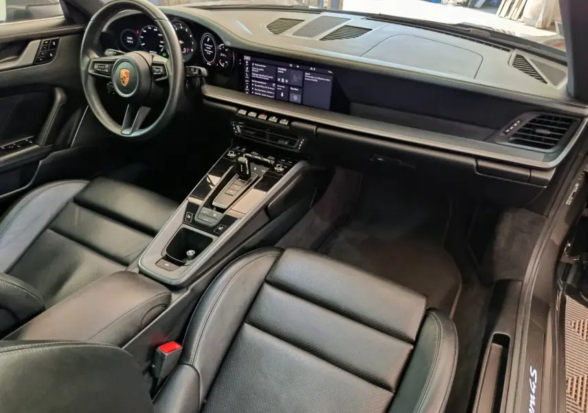 Intérieur noir de la Porsche 911 Carrera 4S 2019 vu côté passager, avec tableau de bord digital et console centrale moderne.