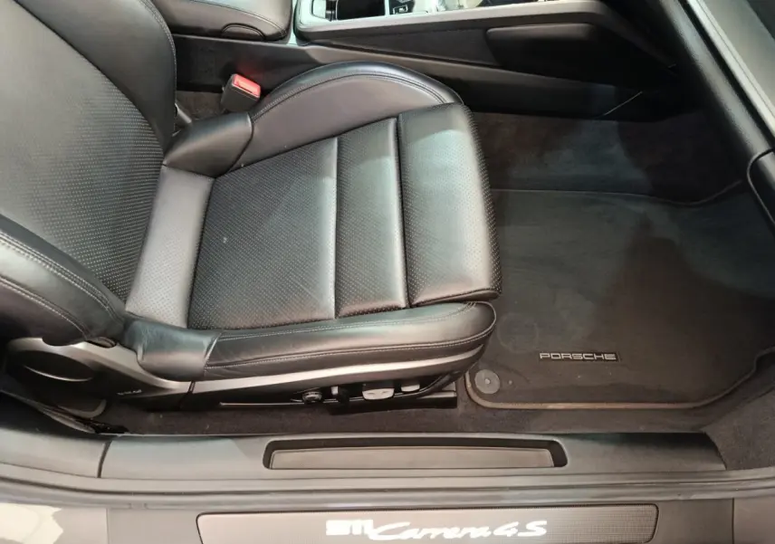 Vue rapprochée du siège conducteur en cuir noir et tapis de sol Porsche d'une Porsche 911 Carrera 4S Coupé 2019.