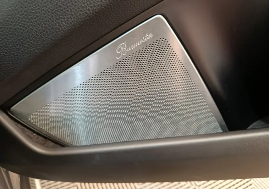 Gros plan sur le haut-parleur Burmester intégré à la porte intérieure noire de la Porsche 911 Carrera 4S Coupé gris foncé.