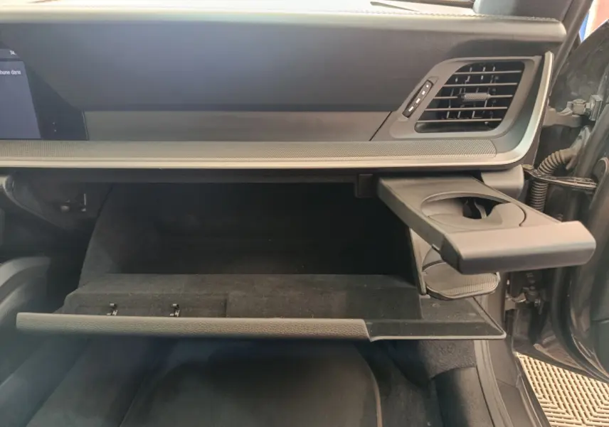 Intérieur côté passager d'une Porsche 911 Carrera 4S 2019, boîte à gants ouverte avec porte-gobelet déployé, finition gris foncé.