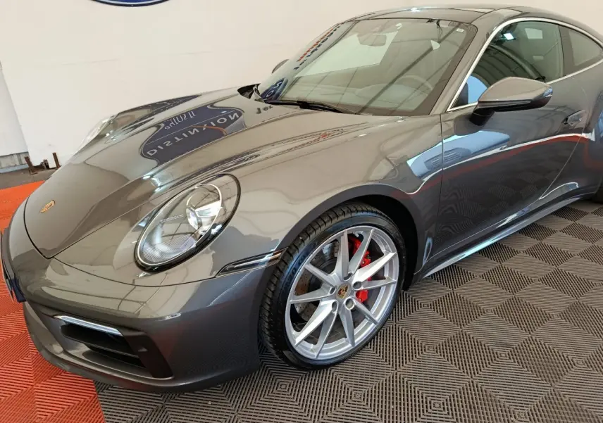 Porsche 911 Carrera 4S Coupé gris foncé vue 3/4 avant droit avec jantes alliage et étriers rouges visibles