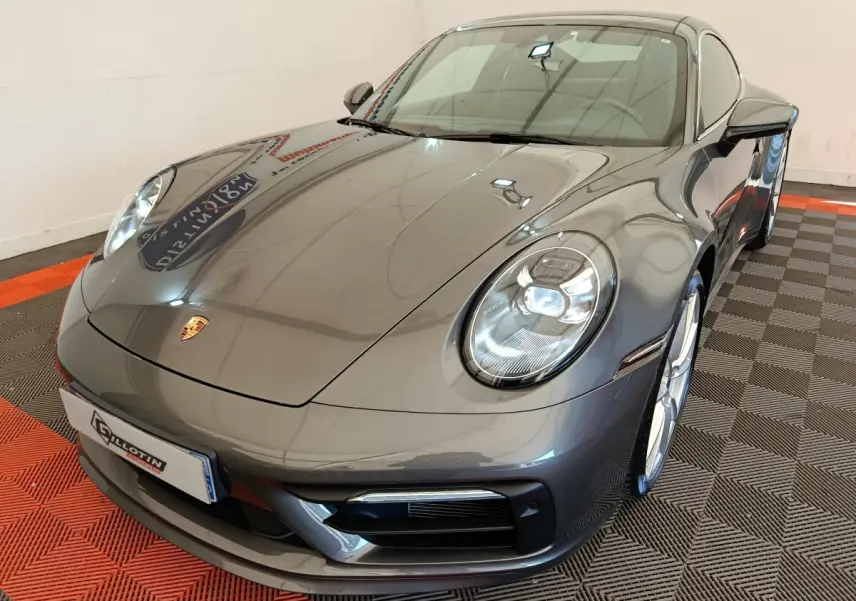 Vue 3/4 avant droite d'une Porsche 911 Carrera 4S Coupé gris foncé brillant avec phares LED et jantes argentées.
