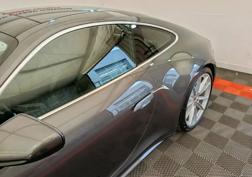 Vue latérale côté droit d'une Porsche 911 Carrera 4S Coupé gris foncé, soulignant la ligne fluide et les jantes sport.