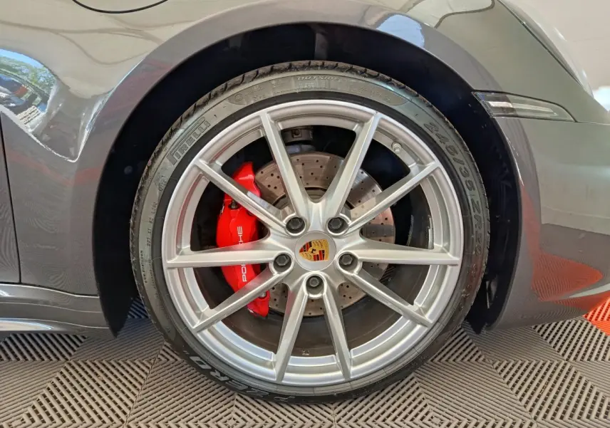 Gros plan sur la roue avant droite grise d'une Porsche 911 Carrera 4S avec étrier de frein rouge et jante argentée.