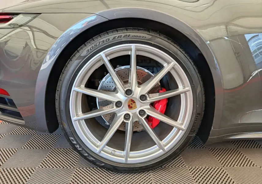 Gros plan sur la roue arrière droite grise d'une Porsche 911 Carrera 4S avec étrier de frein rouge visible.