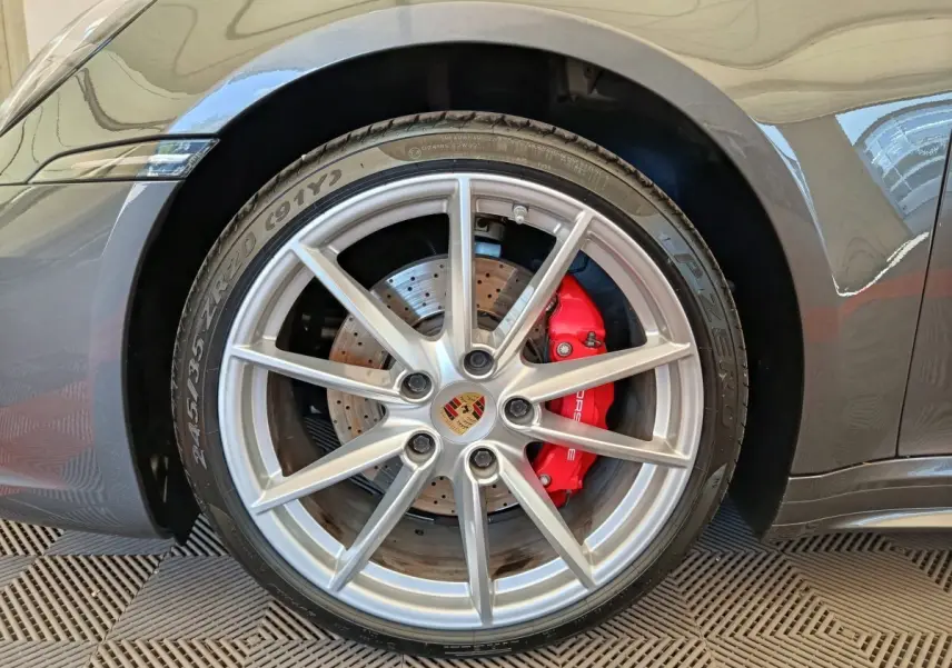Gros plan sur la roue avant droite grise d'une Porsche 911 Carrera 4S avec étrier de frein rouge et jante argentée.