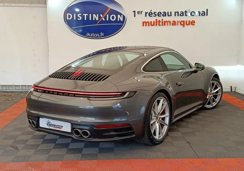 Vue 3/4 arrière droite d'une Porsche 911 Carrera 4S Coupé gris foncé avec feux LED et quadruple sortie d'échappement.