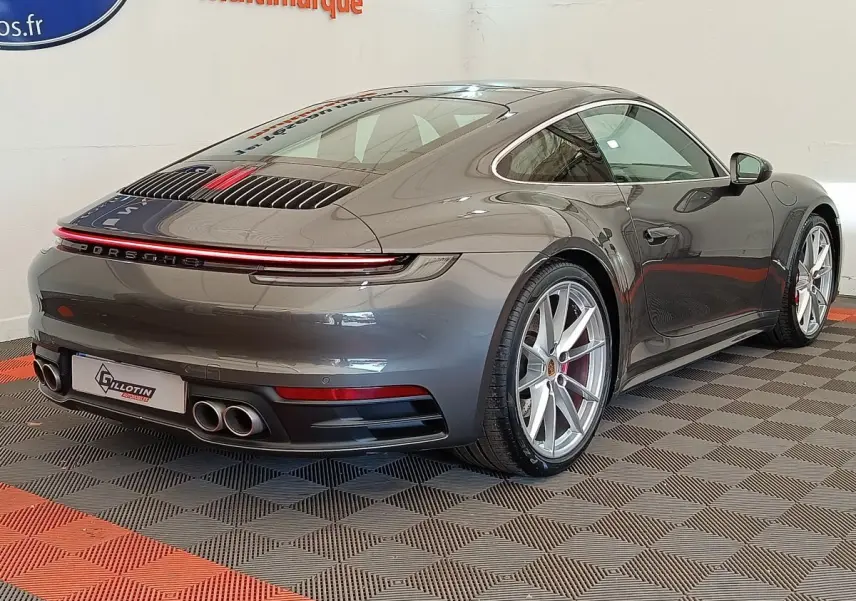 Vue 3/4 arrière droite d'une Porsche 911 Carrera 4S Coupé gris foncé avec feux LED et quadruple sortie d'échappement.