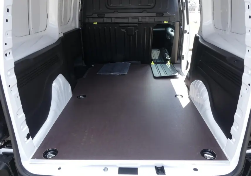 Vue intérieure arrière du Peugeot Partner XL blanc 2025 montrant le plancher bois antidérapant et les anneaux d'arrimage au sol.
