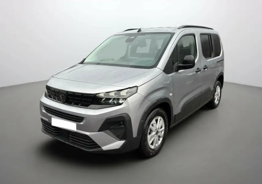 Peugeot Rifter gris artense en 3/4 avant droit, avec barres de toit et vitres arrière surteintées.