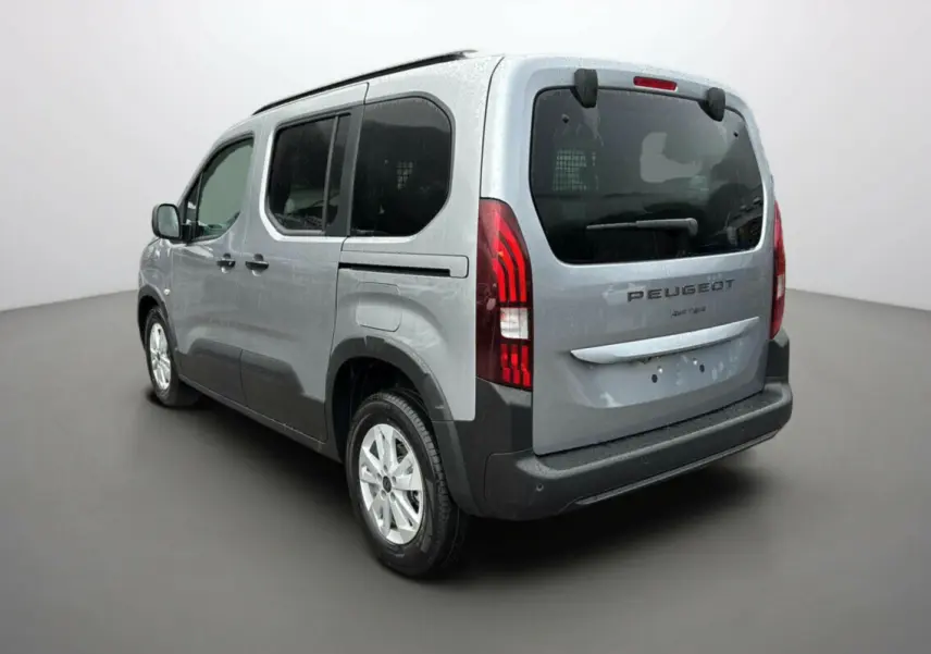 Vue 3/4 arrière droit d’un Peugeot Rifter gris Artense avec vitres surteintées et grille de séparation dans le coffre.
