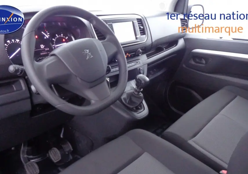 Intérieur avant droit du Peugeot Expert Long 2023, montrant le volant, la boîte manuelle et les sièges gris tissu.