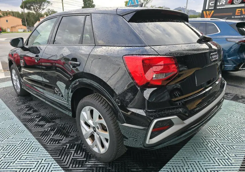 Audi Q2 noir mythic vue 3/4 arrière droit avec vitres surteintées et jantes aluminium 5 branches doubles.