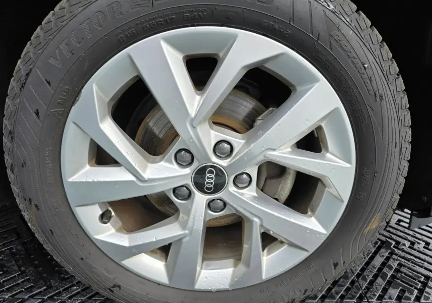 Gros plan sur la jante aluminium 5 branches doubles de l'Audi Q2 noir mythic avec pneu toutes saisons.