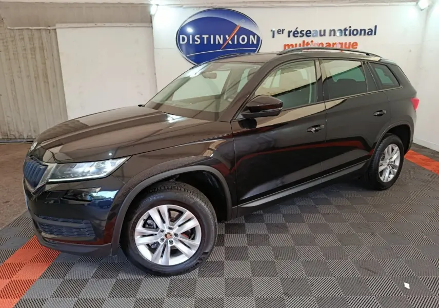 Vue 3/4 avant droite d'un SUV SKODA KODIAQ noir 2021 finition Ambition, roues alliage et barres de toit noires visibles.