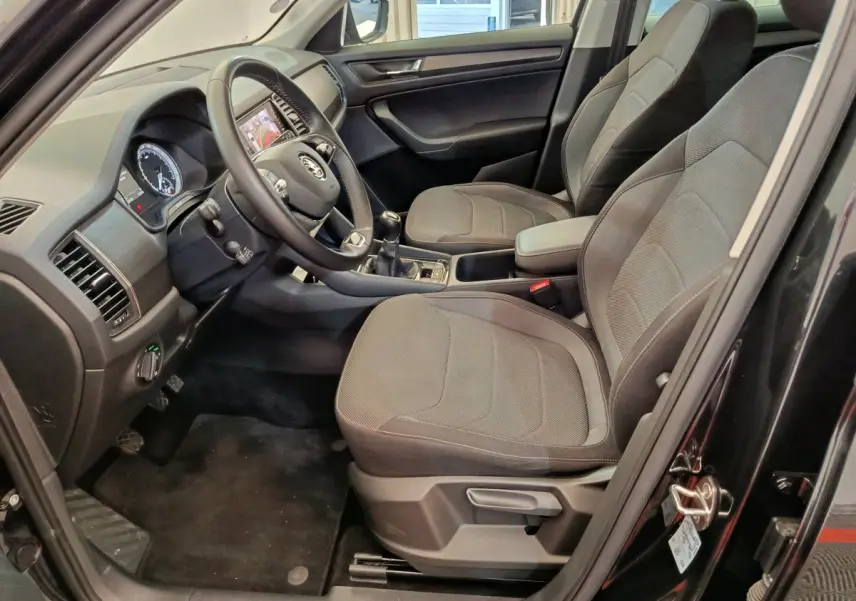 Intérieur avant du Skoda Kodiaq noir 2021, vue côté conducteur montrant sièges tissu gris et tableau de bord moderne.