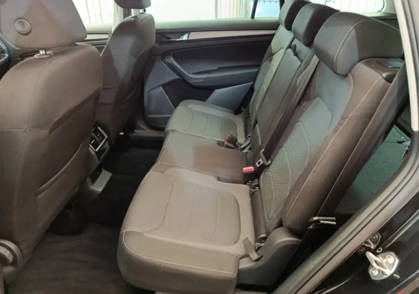 Vue latérale intérieure côté droit du Skoda Kodiaq noir 2021, montrant la banquette arrière en tissu gris avec appuie-têtes.