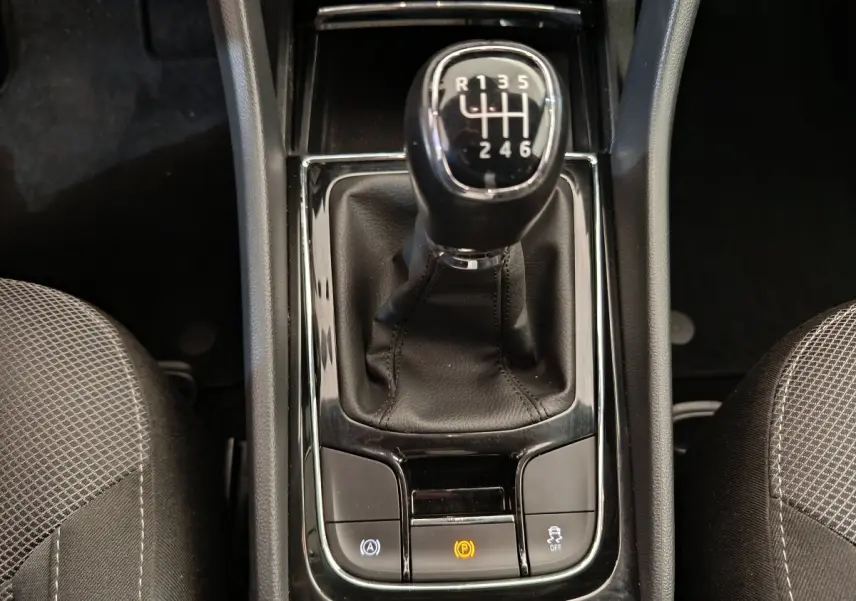 Gros plan sur le levier de vitesses manuel noir du Skoda Kodiaq 2021, entouré des sièges avant en tissu gris.