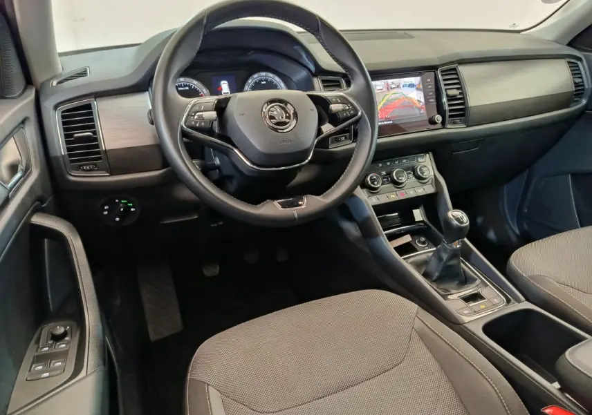 Vue intérieure avant centrée sur le volant cuir Skoda Kodiaq noir, tableau de bord avec écran tactile et levier de vitesse manuel.