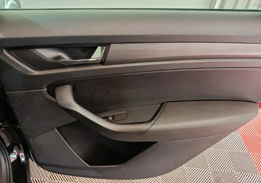 Gros plan sur la porte intérieure côté conducteur du Skoda Kodiaq noir, avec poignée chromée et garniture noire.