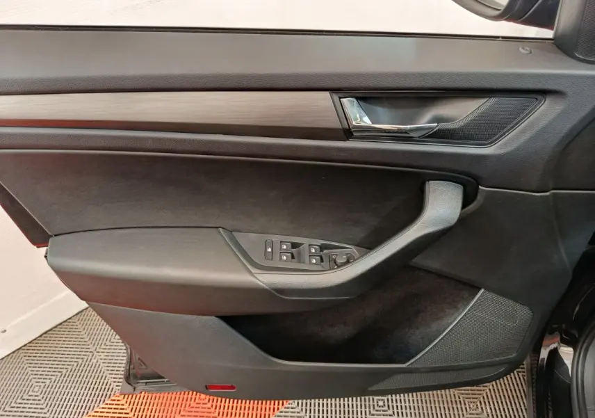 Intérieur côté gauche de la porte avant d'un Skoda Kodiaq noir, avec commandes de vitres et poignée intégrée.