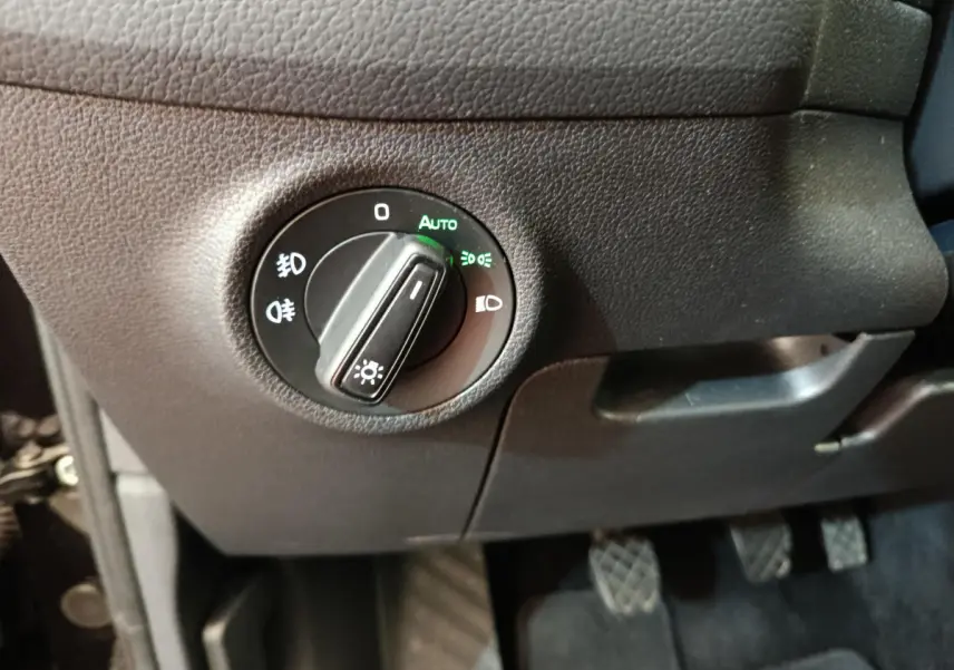 Gros plan sur le bouton de commande des phares en mode automatique dans l'habitacle noir du Skoda Kodiaq noir 2021.
