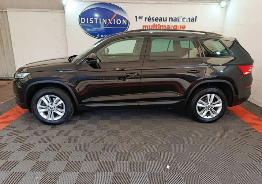 Profil droit d'un SUV SKODA KODIAQ noir 2021 avec toit noir mat et jantes argentées en intérieur showroom
