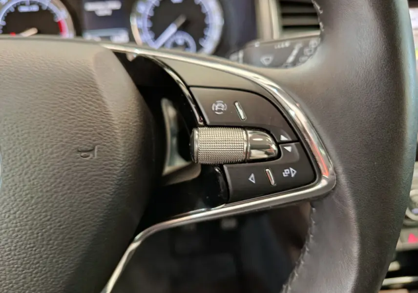 Gros plan sur la partie droite du volant cuir du Skoda Kodiaq noir, avec commandes multifonctions et molette métallique.