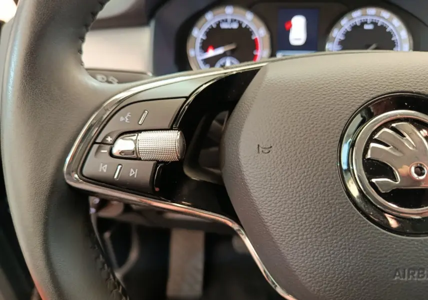 Gros plan sur le volant cuir noir du Skoda Kodiaq 2021, avec commandes multifonctions et logo central chrome.