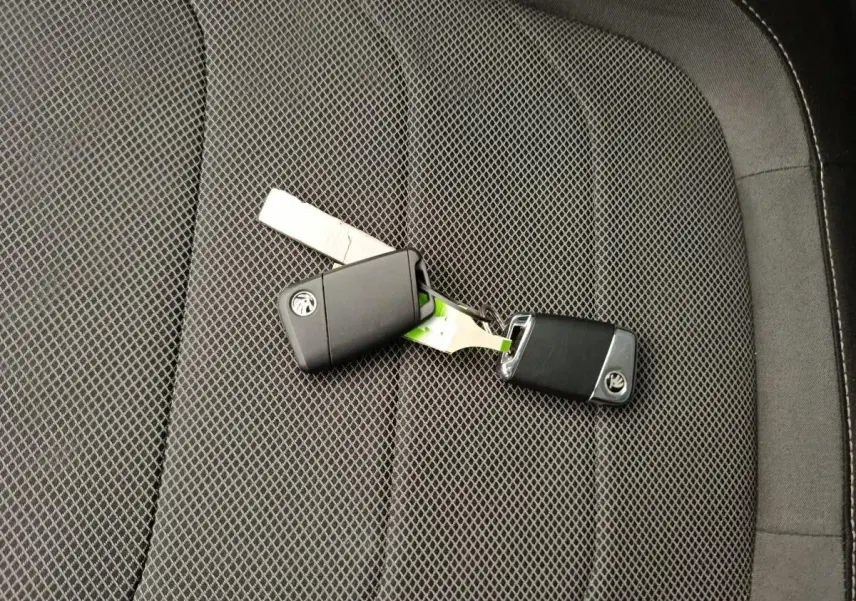 Clé de voiture SKODA posée sur un siège tissu noir à motifs géométriques à l'intérieur du KODIAQ 2021.