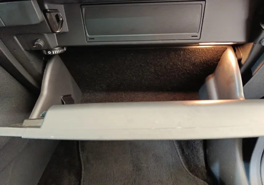 Vue rapprochée de la boîte à gants ouverte avec éclairage intérieur dans un Skoda Kodiaq noir 2021.