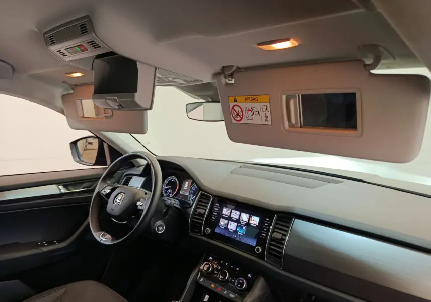 Intérieur avant du Skoda Kodiaq noir 2021, vue côté conducteur avec tableau de bord et écran tactile allumés.