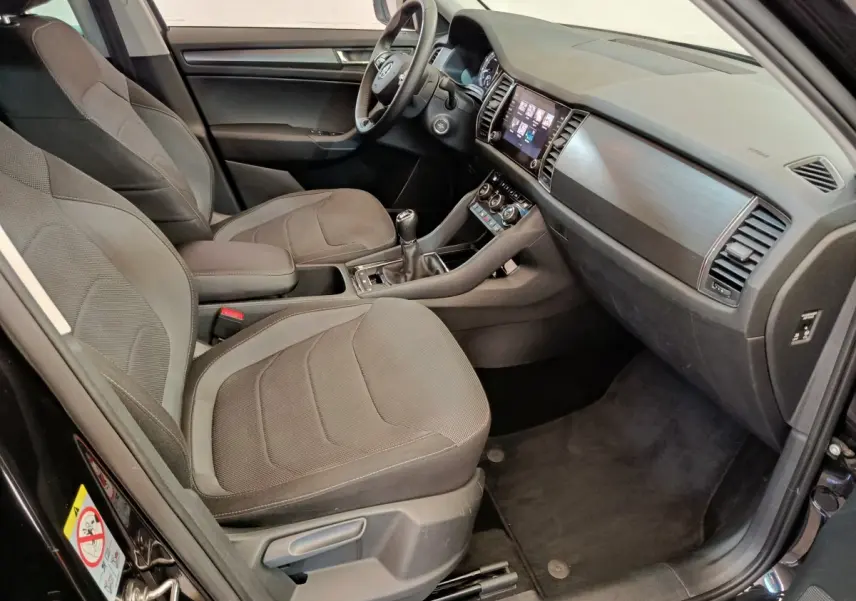 Intérieur avant du Skoda Kodiaq noir 2021, vue côté conducteur montrant sièges tissu et tableau de bord moderne.