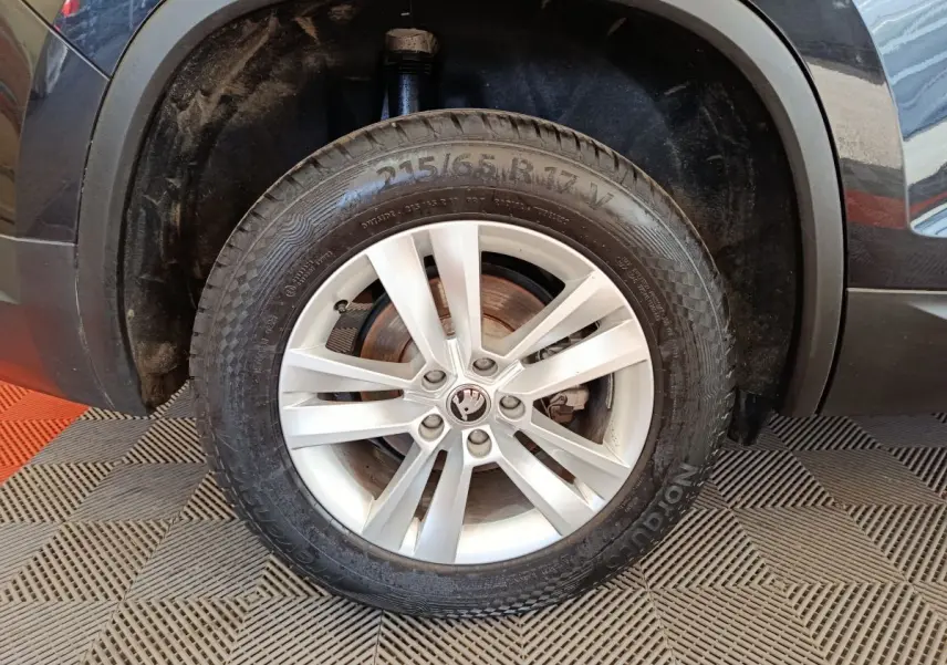 Gros plan sur la roue avant gauche noire d'un Skoda Kodiaq 2021 avec jante alliage argentée et logo central.