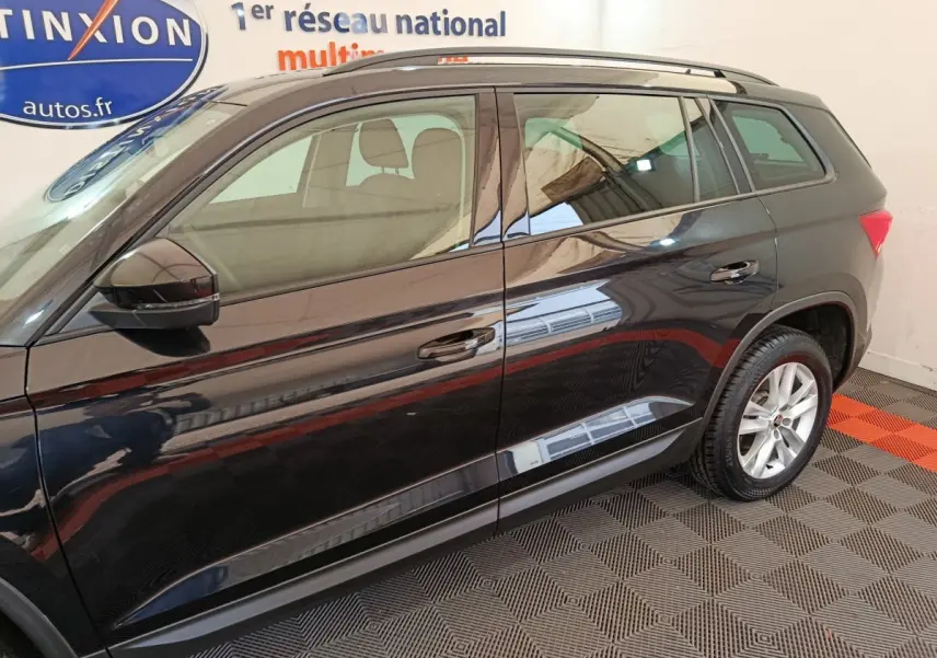 Vue latérale côté gauche d'un Skoda Kodiaq noir 2021 stationné en intérieur avec jantes alliage visibles.