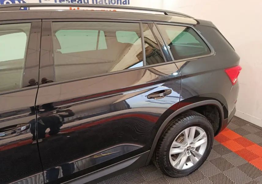 Vue latérale droite d'un SUV SKODA KODIAQ noir 2021 avec jantes alliage et barres de toit chromées.
