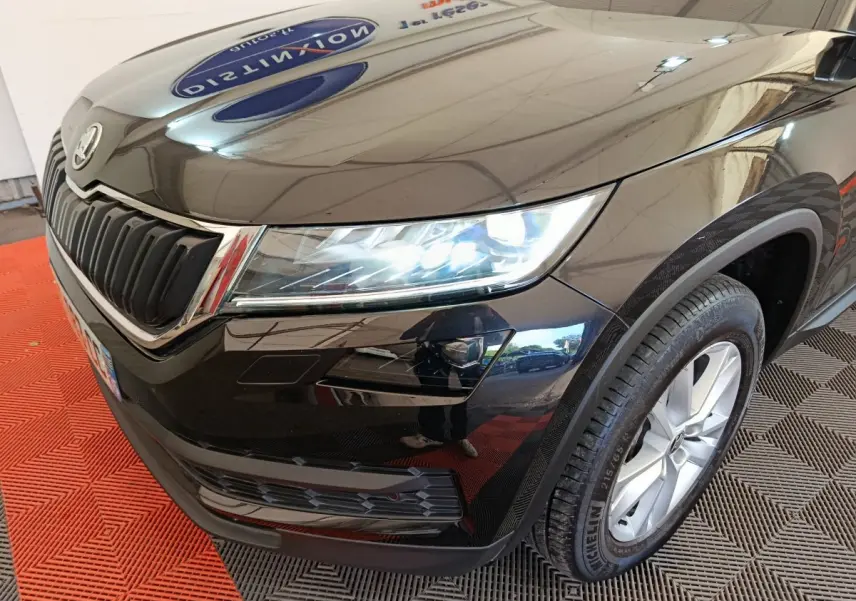 Vue 3/4 avant droit d'un Skoda Kodiaq noir avec phares LED allumés et jantes alliage visibles.
