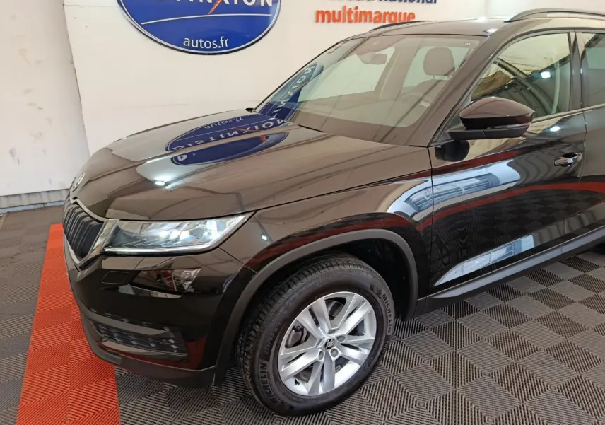 Vue 3/4 avant droit d'un Skoda Kodiaq noir brillant avec jantes alliage et phares LED dans un showroom.