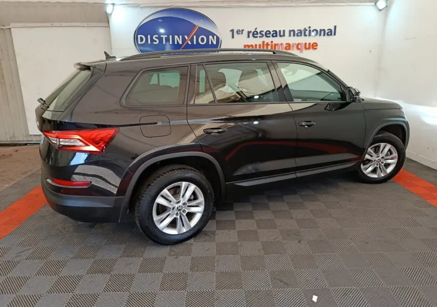 Vue latérale droite d'un SKODA KODIAQ noir 2021 avec jantes alliage et toit noir dans un showroom.